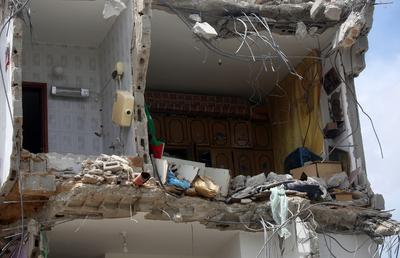 Palestinians inspect the damage around a destroyed building after Israeli troops besieged it and killed-stock-photo