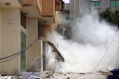 Palestinians inspect the damage around a destroyed building after Israeli troops besieged it and killed-stock-photo