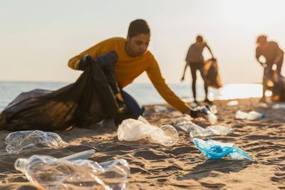 Tag der Erde. Freiwillige Aktivisten sammelt M?ll Reinigung von Strand K?stenzone. Frau mans mit M?ll in M?llsack auf Ozean Ufer. Umweltschutz K?stenzone Reinigung. Unscharfes Bild.-stock-foto