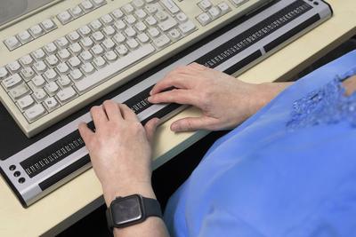 Blinde Frau arbeitet mit einer Braillezeile. Die Braillezeile, kurz Zeile, oder Brailledisplay ist ein Computer-Ausgabeg-stock-foto