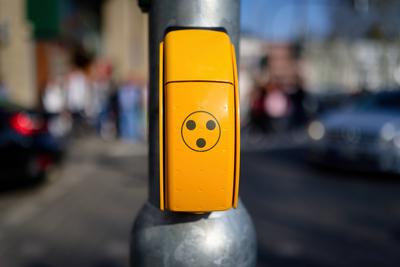 Ein gelber Knopf mit dem Drei-Punkte-Symbol f?r blinde und sehbehinderte Menschen an einem Fu?g?nger?berweg in einer st?-stock-foto
