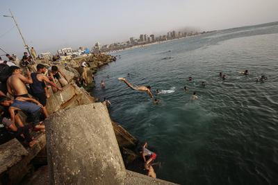 Palestinians, struggling with harsh living conditions due to ongoing Israeli attacks on the Gaza Strip and an intensifying heatwave, gather on the coast to cool off, spending the evening hours by the seaside to escape the stifling heat inside their tents-stock-foto
