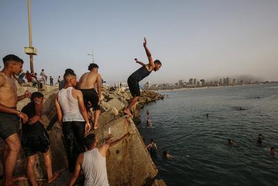 Palestinians, struggling with harsh living conditions due to ongoing Israeli attacks on the Gaza Strip and an intensifying heatwave, gather on the coast to cool off, spending the evening hours by the seaside to escape the stifling heat inside their tents-stock-foto
