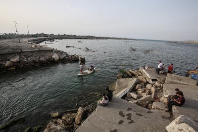 Palestinians, struggling with harsh living conditions due to ongoing Israeli attacks on the Gaza Strip and an intensifying heatwave, gather on the coast to cool off, spending the evening hours by the seaside to escape the stifling heat inside their tents-stock-foto