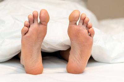 Bavaria, Germany - November 26, 2023: The feet of a young man look out from under a white comforter in bed *** Die F??e-stock-foto