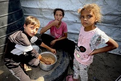 Palestinians wait in long queues to receive pots of food distributed by charitable organizations, as they face food crisis-stock-photo