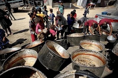 Palestinians wait in long queues to receive pots of food distributed by charitable organizations, as they face food crisis-stock-photo