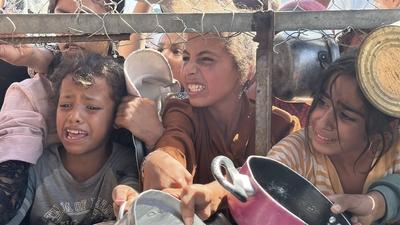 Palestinians wait in long queues to receive pots of food distributed by charitable organizations, as they face food crisis-stock-photo