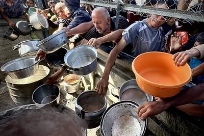 Palestinians wait in long queues to receive pots of food distributed by charitable organizations, as they face food crisis-stock-photo