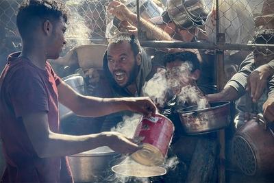 Palestinians wait in long queues to receive pots of food distributed by charitable organizations, as they face food crisis-stock-photo