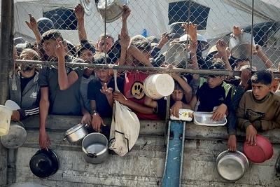 Palestinians wait in long queues to receive pots of food distributed by charitable organizations, as they face food crisis-stock-photo