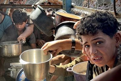 Palestinians wait in long queues to receive pots of food distributed by charitable organizations, as they face food crisis-stock-photo
