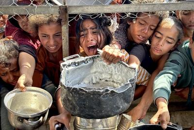 Palestinians wait in long queues to receive pots of food distributed by charitable organizations, as they face food crisis-stock-photo