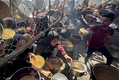 Palestinians wait in long queues to receive pots of food distributed by charitable organizations, as they face food crisis-stock-photo