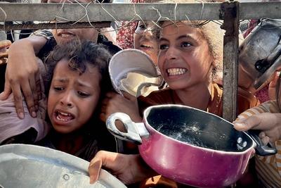 Palestinians wait in long queues to receive pots of food distributed by charitable organizations, as they face food crisis-stock-photo