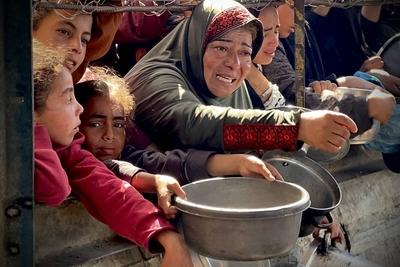 Palestinians wait in long queues to receive pots of food distributed by charitable organizations, as they face food crisis-stock-photo