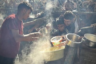 Palestinians wait in long queues to receive pots of food distributed by charitable organizations, as they face food crisis-stock-photo