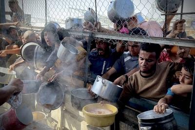 Palestinians wait in long queues to receive pots of food distributed by charitable organizations, as they face food crisis-stock-photo