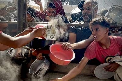 Palestinians wait in long queues to receive pots of food distributed by charitable organizations, as they face food crisis-stock-photo