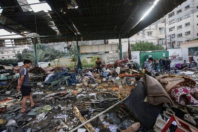 Palestinians inspect the area among the rubbles of destroyed building following an Israeli airstrike on Fahmi Al-Jarjawi school sheltering displaced people, which killed 30 people in Gaza City-stock-foto