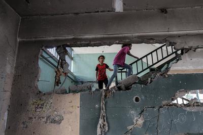 Palestinians inspect the area among the rubbles of destroyed building following an Israeli airstrike on Fahmi Al-Jarjawi school sheltering displaced people, which killed 30 people in Gaza City-stock-foto