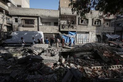 Palestinians inspect the area among the rubbles of destroyed building following an Israeli airstrike on Fahmi Al-Jarjawi school sheltering displaced people, which killed 30 people in Gaza City-stock-foto