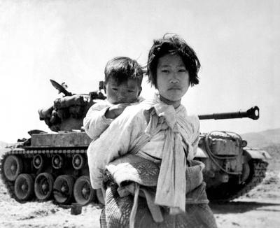 Korea: With her brother on her back a war-weary Korean girl trudges by a M-26 tank at Haengju. Korean War (1950-1953). T-stock-photo
