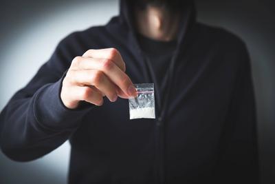 Mann in Sweatshirt und Kapuzenpulli, gesichtslos, h?lt kleine T?te mit wei?er Substanz - Droge, Konzept der Drogensucht, -abh?ngigkeit und -verteilung-stock-photo