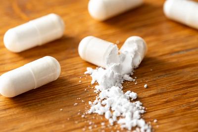 Bavaria, Germany - April 16, 2025: Cracked capsules on wood show fine, white powder - a symbol for the problem of drug c-stock-foto