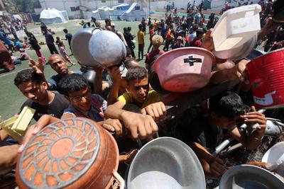 Internally displaced Palestinians gather in a charity kitchen to receive limited rations amid a shortage of food, in Nuseirat Palestinian refugee camp-stock-foto