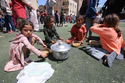 Internally displaced Palestinians gather in a charity kitchen to receive limited rations amid a shortage of food, in Nuseirat Palestinian refugee camp-stock-foto