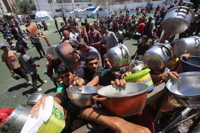 Internally displaced Palestinians gather in a charity kitchen to receive limited rations amid a shortage of food, in Nuseirat Palestinian refugee camp-stock-foto