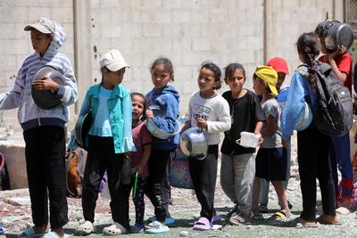 Internally displaced Palestinians gather in a charity kitchen to receive limited rations amid a shortage of food, in Nuseirat Palestinian refugee camp-stock-foto
