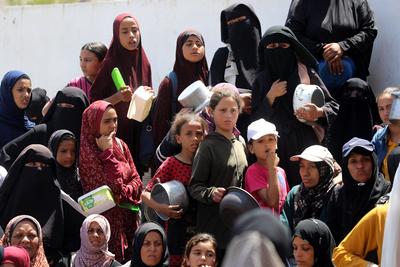 Internally displaced Palestinians gather in a charity kitchen to receive limited rations amid a shortage of food, in Nuseirat Palestinian refugee camp-stock-foto