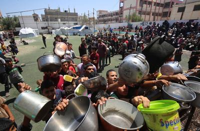 Internally displaced Palestinians gather in a charity kitchen to receive limited rations amid a shortage of food, in Nuseirat Palestinian refugee camp-stock-foto