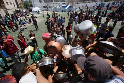 Internally displaced Palestinians gather in a charity kitchen to receive limited rations amid a shortage of food, in Nuseirat Palestinian refugee camp-stock-foto