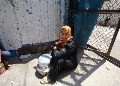 Internally displaced Palestinians gather in a charity kitchen to receive limited rations amid a shortage of food, in Nuseirat Palestinian refugee camp-stock-foto