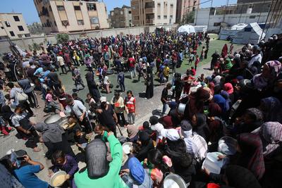 Internally displaced Palestinians gather in a charity kitchen to receive limited rations amid a shortage of food, in Nuseirat Palestinian refugee camp-stock-foto