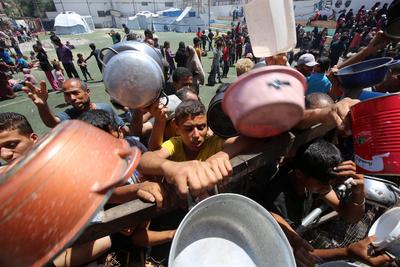 Internally displaced Palestinians gather in a charity kitchen to receive limited rations amid a shortage of food, in Nuseirat Palestinian refugee camp-stock-foto