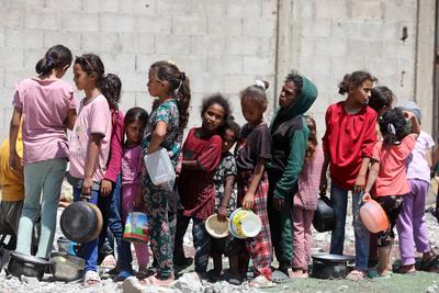 Internally displaced Palestinians gather in a charity kitchen to receive limited rations amid a shortage of food, in Nuseirat Palestinian refugee camp-stock-foto