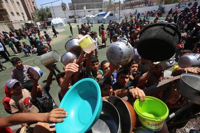 Internally displaced Palestinians gather in a charity kitchen to receive limited rations amid a shortage of food, in Nuseirat Palestinian refugee camp-stock-foto