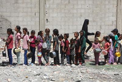 Internally displaced Palestinians gather in a charity kitchen to receive limited rations amid a shortage of food, in Nuseirat Palestinian refugee camp-stock-foto