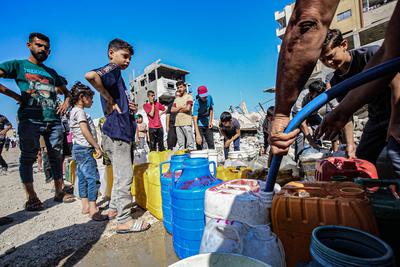 Palestinians carry jerry cans filled with water distributed by a water tanker, in Gaza-stock-foto