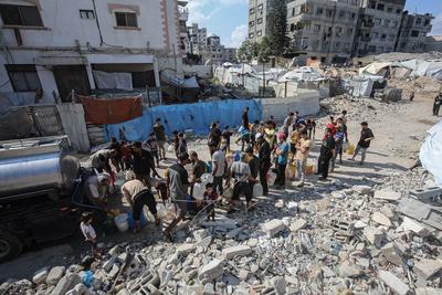 Palestinians carry jerry cans filled with water distributed by a water tanker, in Gaza-stock-foto
