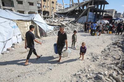 Palestinians carry jerry cans filled with water distributed by a water tanker, in Gaza-stock-foto