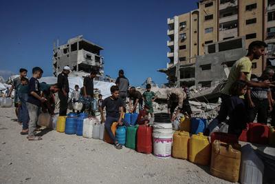 Palestinians carry jerry cans filled with water distributed by a water tanker, in Gaza-stock-foto