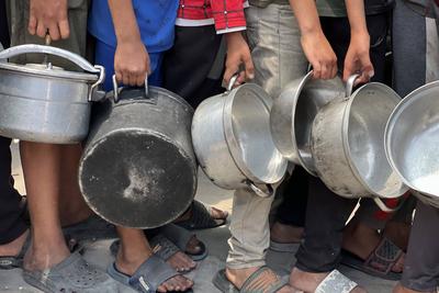 Internally displaced Palestinians gather in a charity kitchen to receive limited rations amid a shortage of food-stock-foto