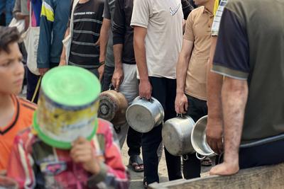 Internally displaced Palestinians gather in a charity kitchen to receive limited rations amid a shortage of food-stock-foto