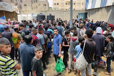 Internally displaced Palestinians gather in a charity kitchen to receive limited rations amid a shortage of food-stock-foto