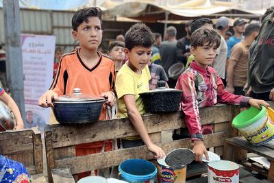 Internally displaced Palestinians gather in a charity kitchen to receive limited rations amid a shortage of food-stock-foto